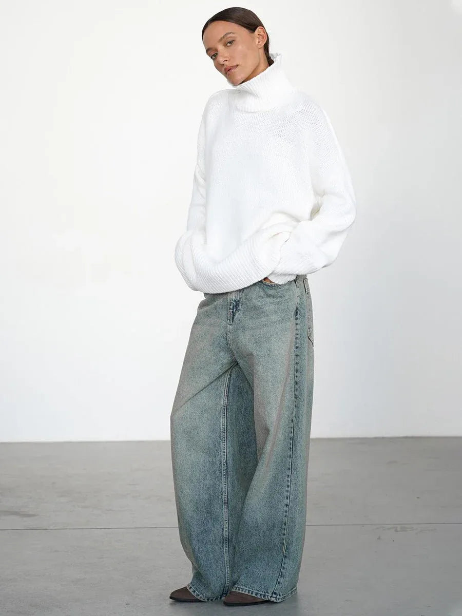 Model with hands in pockets wearing an oversized white turtleneck sweater