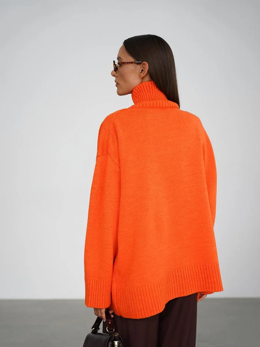 Woman wearing an orange oversized high neck sweater with dark trousers
