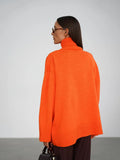 Woman wearing an orange oversized high neck sweater with dark trousers