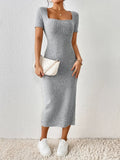 Woman holding a white handbag and wearing a grey ribbed knit midi dress