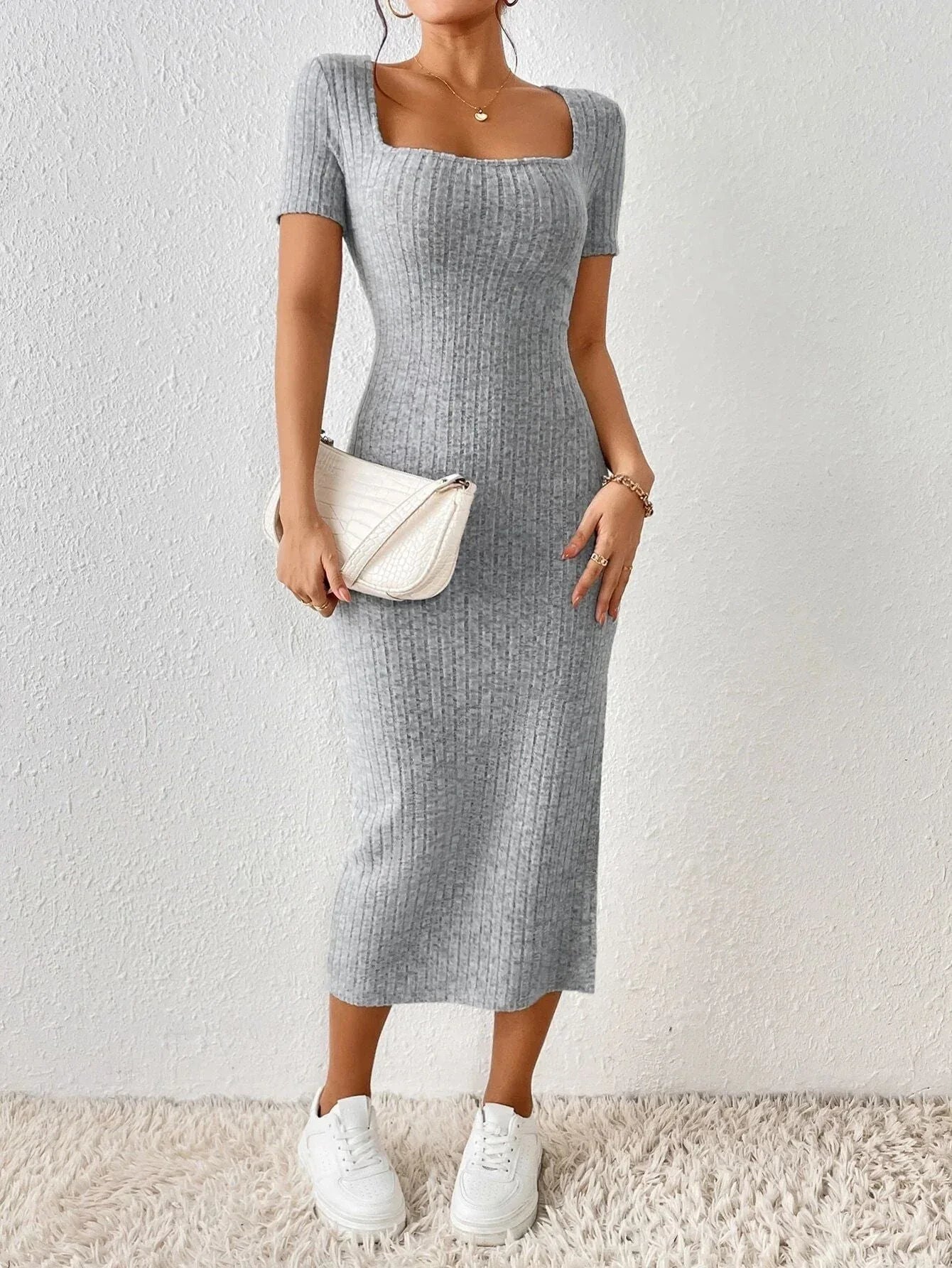 Woman holding a white handbag and wearing a grey ribbed knit midi dress