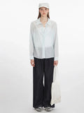 Woman wearing a light blue oversized button-down shirt with dark wide-leg jeans