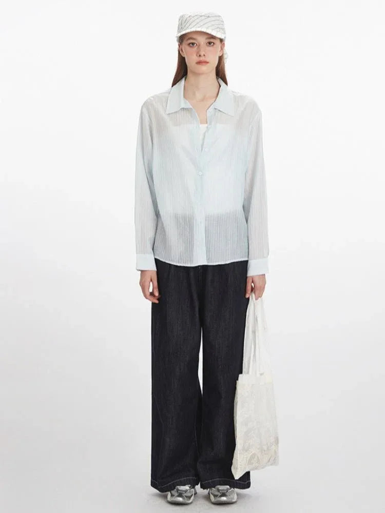 Woman wearing a light blue oversized button-down shirt with dark wide-leg jeans