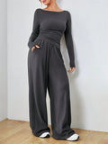 Woman wearing a dark gray boat neck long sleeve top with ruched waist and wide leg pants