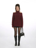 Woman wearing a burgundy cold shoulder halter neck sweater