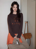 Full body shot of a woman in a dark brown long sleeve top and beige trousers.