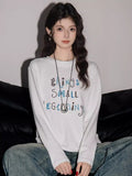 Woman wearing a dark brown long sleeve top with contrasting orange letter embroidery. - View 6 | WEUXS