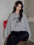 Close-up of the embroidered puppy graphic on a grey sweatshirt