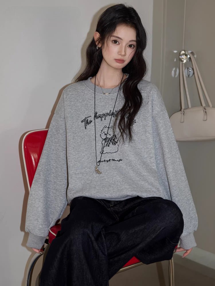 Close-up of the embroidered puppy graphic on a grey sweatshirt