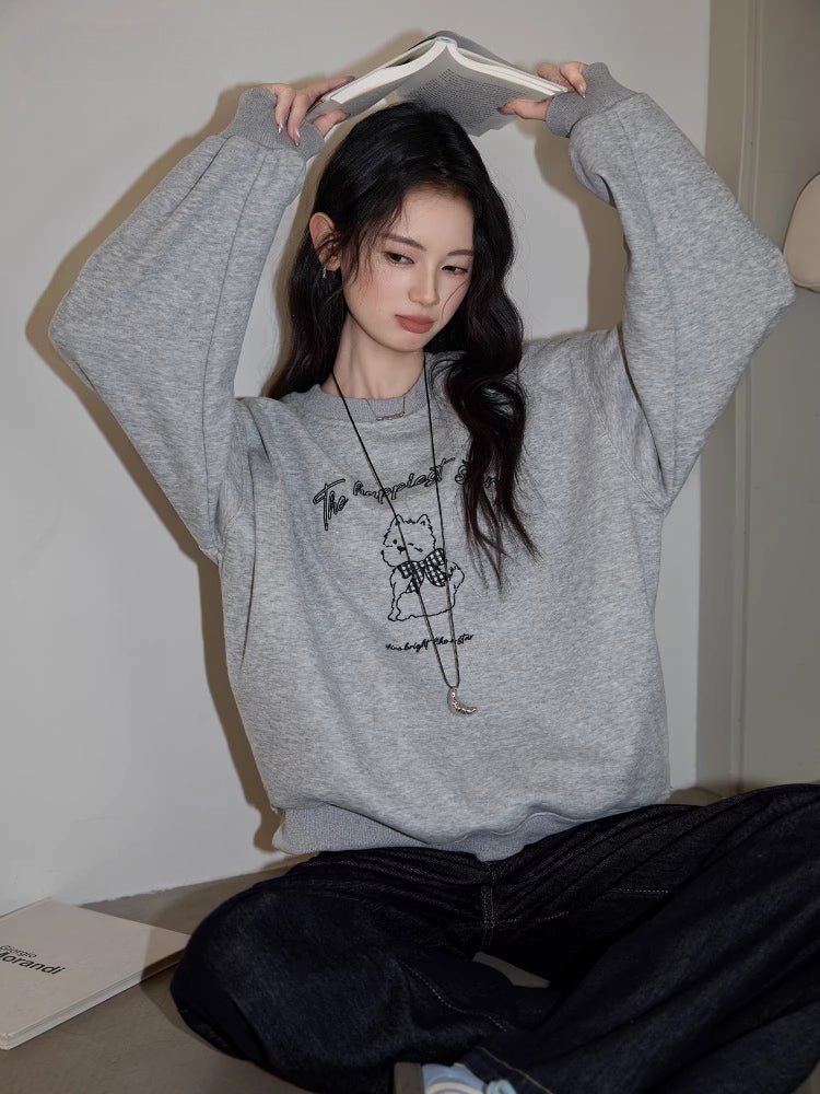 Woman wearing a heather grey embroidered puppy graphic sweatshirt
