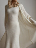 Close-up of a woman wearing a white fitted knit dress and draped cardigan