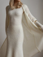 Close-up of a woman wearing a white fitted knit dress and draped cardigan