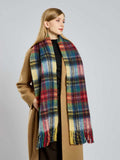 Woman in a camel coat with a colorful plaid scarf draped around her neck