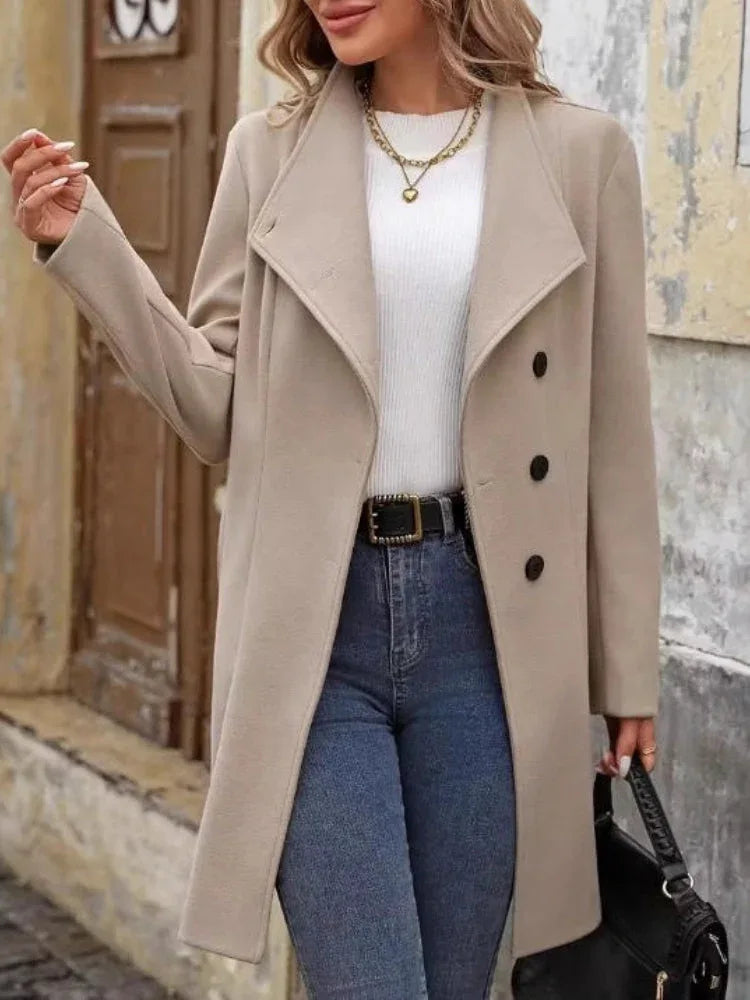 Woman wearing a beige wool blend coat with notch lapel, button detailing, and jeans