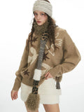 Front view of a woman wearing a tan intarsia knit sweater with birds and stars, a white textured mini skirt, and a patterned scarf.