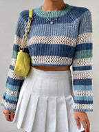 Woman wearing a blue, white, and green striped crochet knit cropped sweater with bell sleeves.