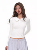 Model wearing a white long-sleeve cropped top with a Peter Pan collar and button placket.