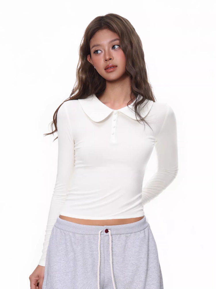 Model wearing a white long-sleeve cropped top with a Peter Pan collar and button placket.