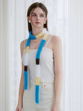 Front view of a woman in a white ribbed camisole and cream pants, showcasing a long, fuzzy knit scarf with horizontal color blocks.