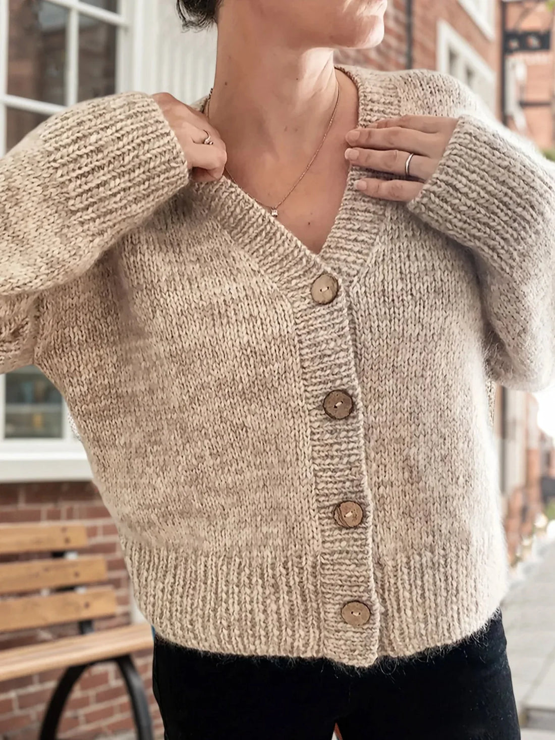 Woman wearing a beige knit cardigan with a v-neck and button front closure