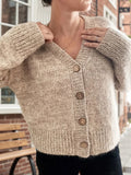 Woman wearing a beige knit cardigan with a v-neck and button front closure