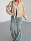 Woman styling a beige corduroy cropped jacket with wide-leg jeans and a grey crop top.