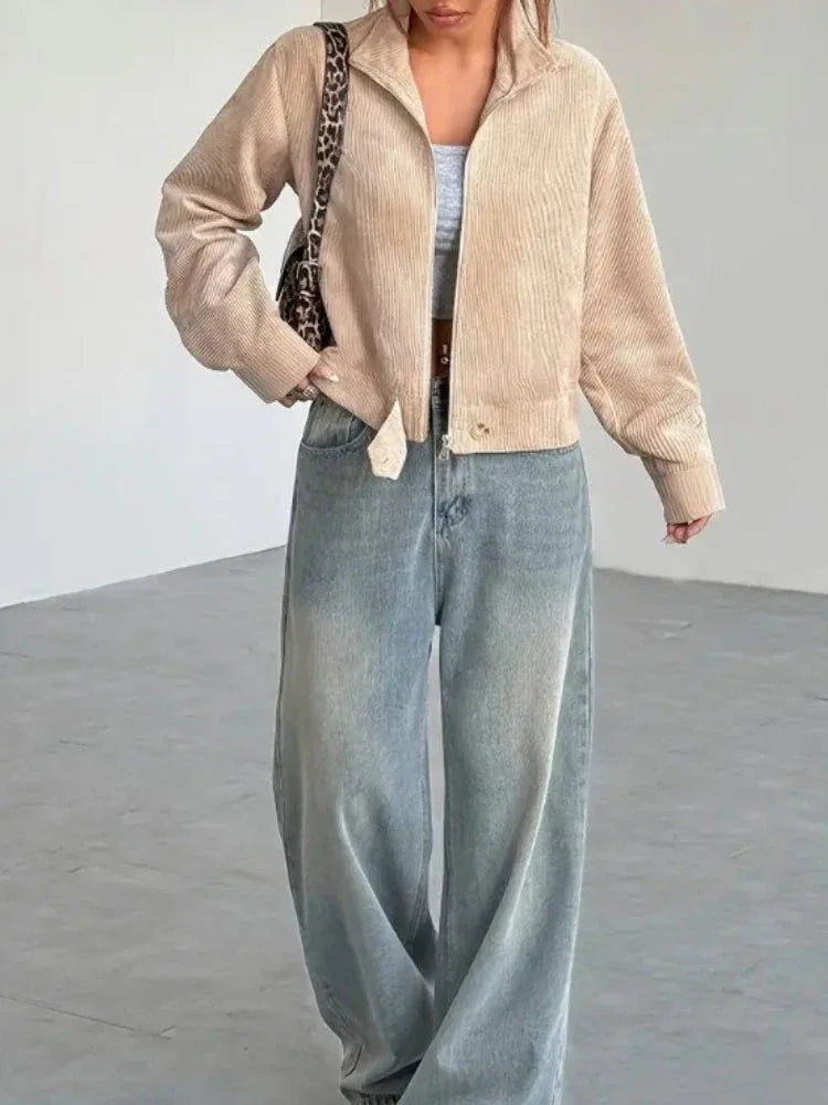Woman styling a beige corduroy cropped jacket with wide-leg jeans and a grey crop top.