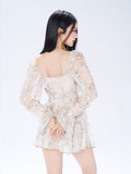 Back view of a woman in a white floral print mini dress with long bishop sleeves.
