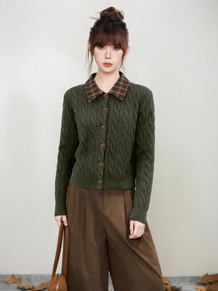 Woman wearing a dark green cable knit cardigan with a brown plaid collar and brown buttons.