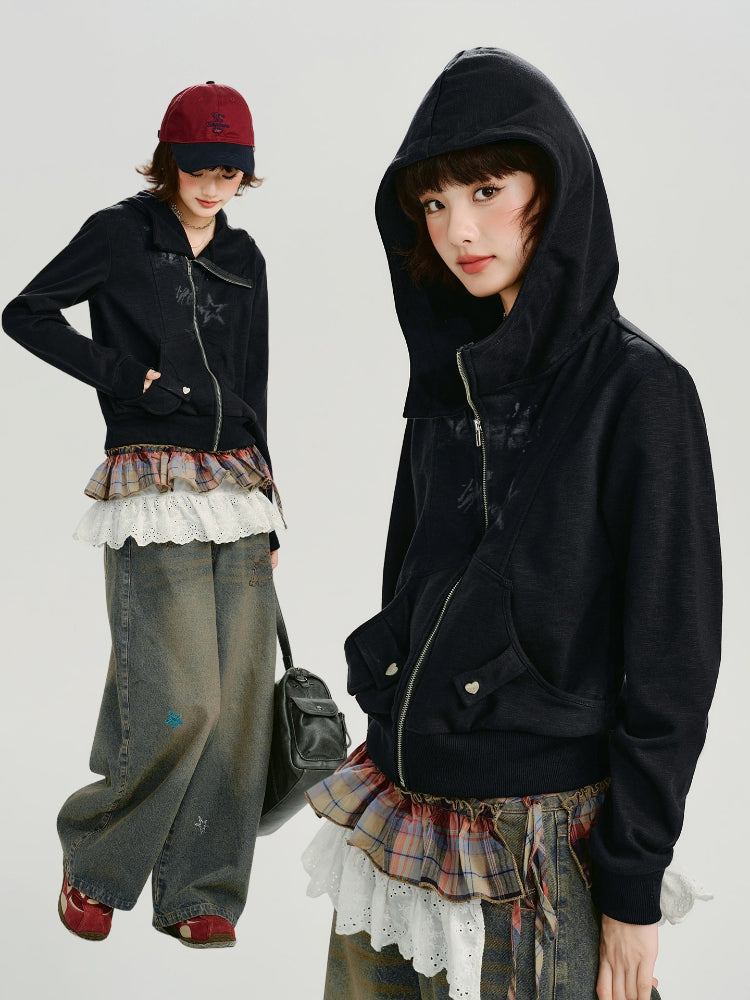 Full body shot of a woman in a black zip-up hoodie, styled with layered skirts and wide-leg jeans.