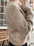 Side view of a woman in a beige knit cardigan with relaxed sleeves