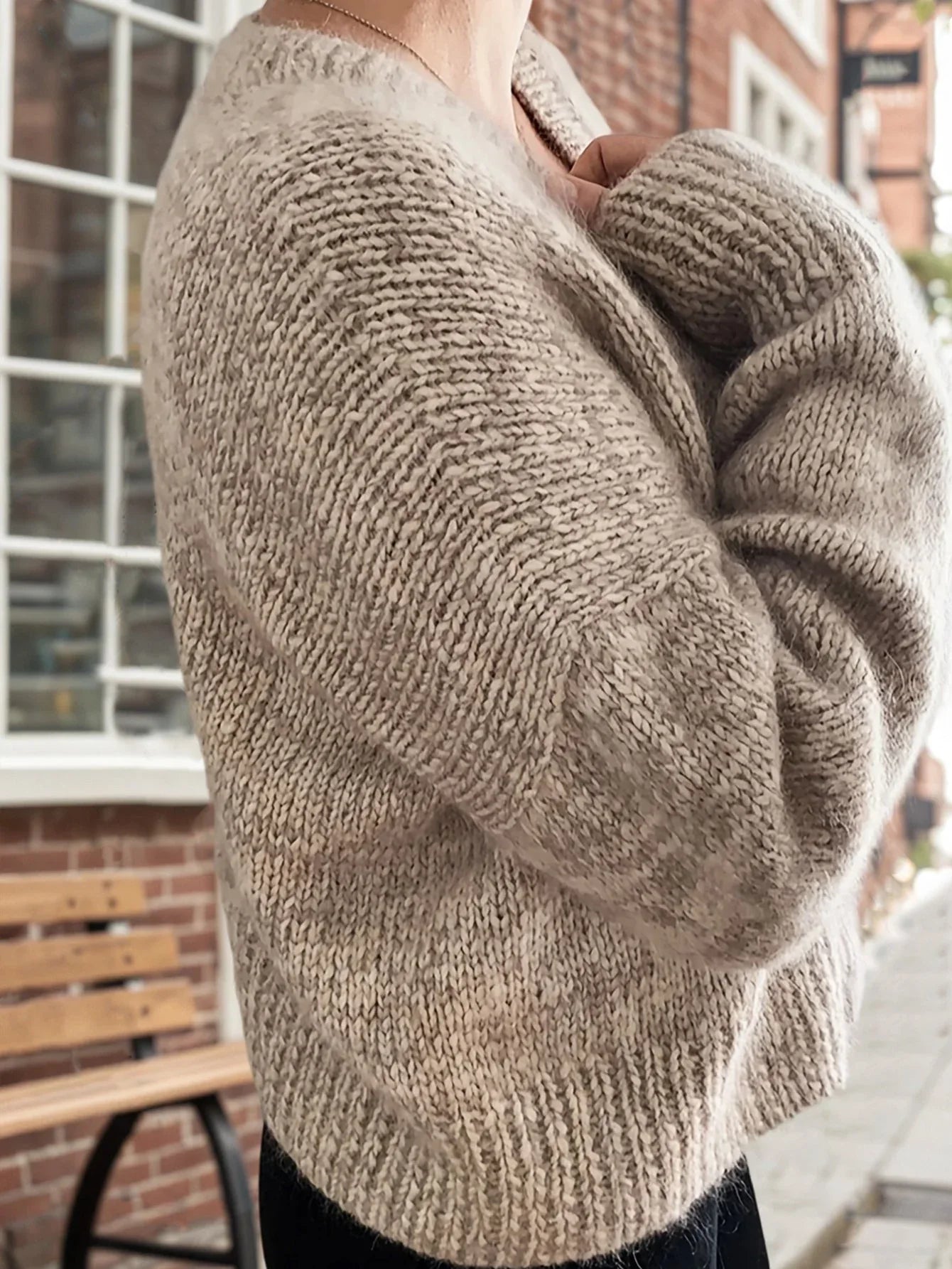 Side view of a woman in a beige knit cardigan with relaxed sleeves