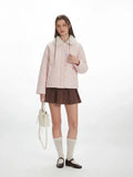 Full body shot of a woman modeling a pink quilted jacket.