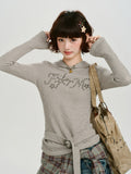 Close-up of the grey ribbed knit hooded long sleeve top with embellishments.