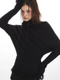 Close-up of a woman's face and shoulders wearing a black turtleneck sweater with dolman sleeves