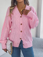 Woman holding a white handbag while wearing a pink cable knit cardigan