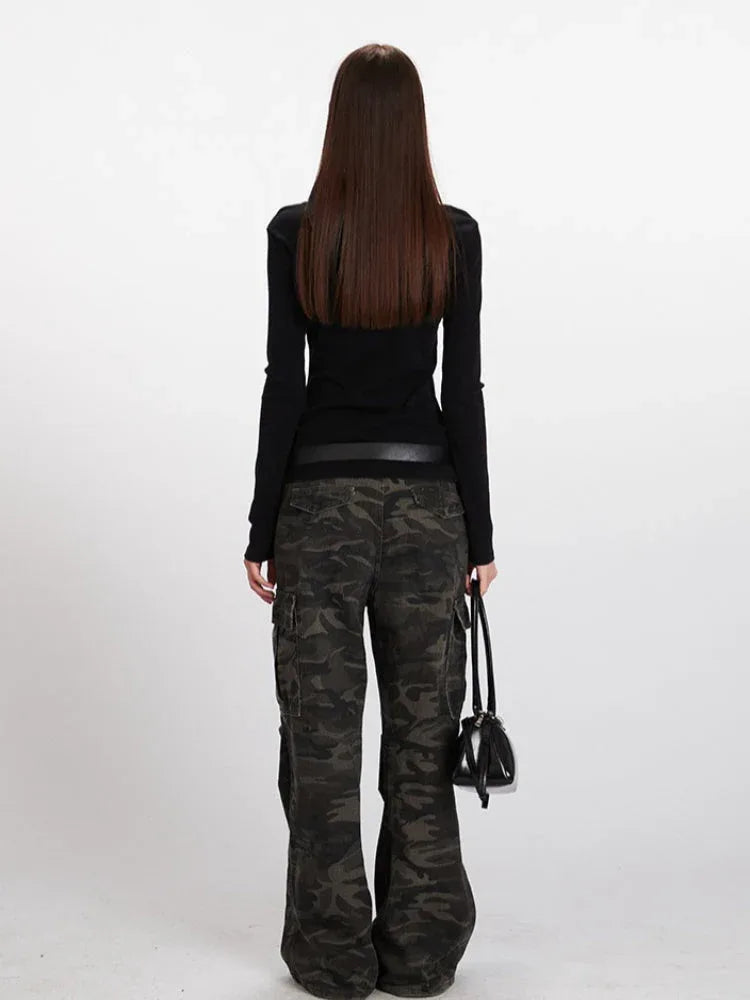Model wearing a black long-sleeve ribbed top with a square neckline and a detachable scarf, paired with camouflage cargo pants and a black belt.