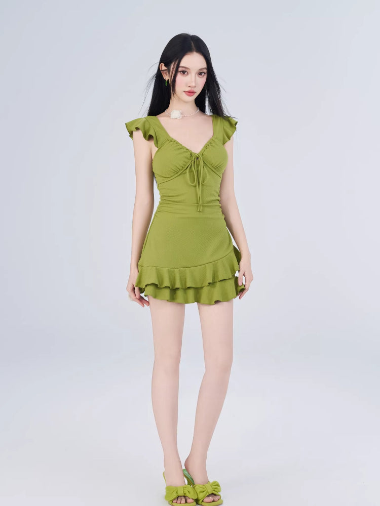 Full body shot of a woman in a lime green fit and flare mini dress with tiered ruffled hem.