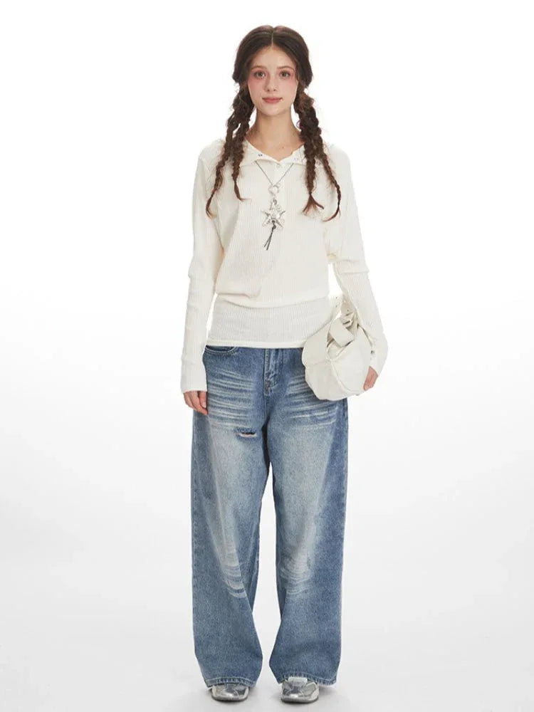 Woman wearing a white ribbed knit long-sleeve top with a collared button-up neckline and a detachable hood, paired with light-wash baggy jeans and a white handbag.