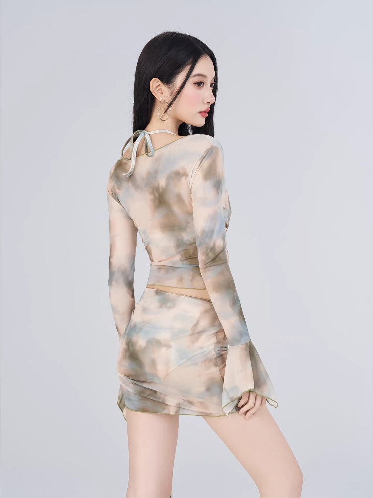 Rear view of a woman in a sheer abstract print two-piece set, showing the back of the top and the ruched skirt.