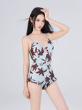 Woman wearing a light blue one-piece swimsuit with spaghetti straps and a floral print