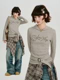 Full body shot of a model wearing a grey ribbed knit hooded long sleeve top, tied flannel shirt, and denim jeans.