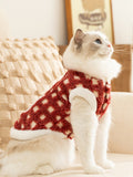 Ragdoll cat wearing a red and white checkered fleece pet vest, looking upwards