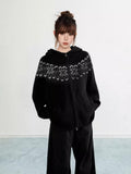 Woman wearing a black Fair Isle knit hoodie with snowflake pattern and zipper