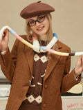 Woman smiling and holding a colorful striped scarf while wearing a brown blazer.