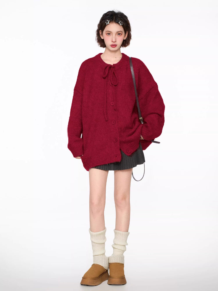 Woman wearing a red knit cardigan with a tie closure and button front, paired with a pleated skirt and knee-high socks.