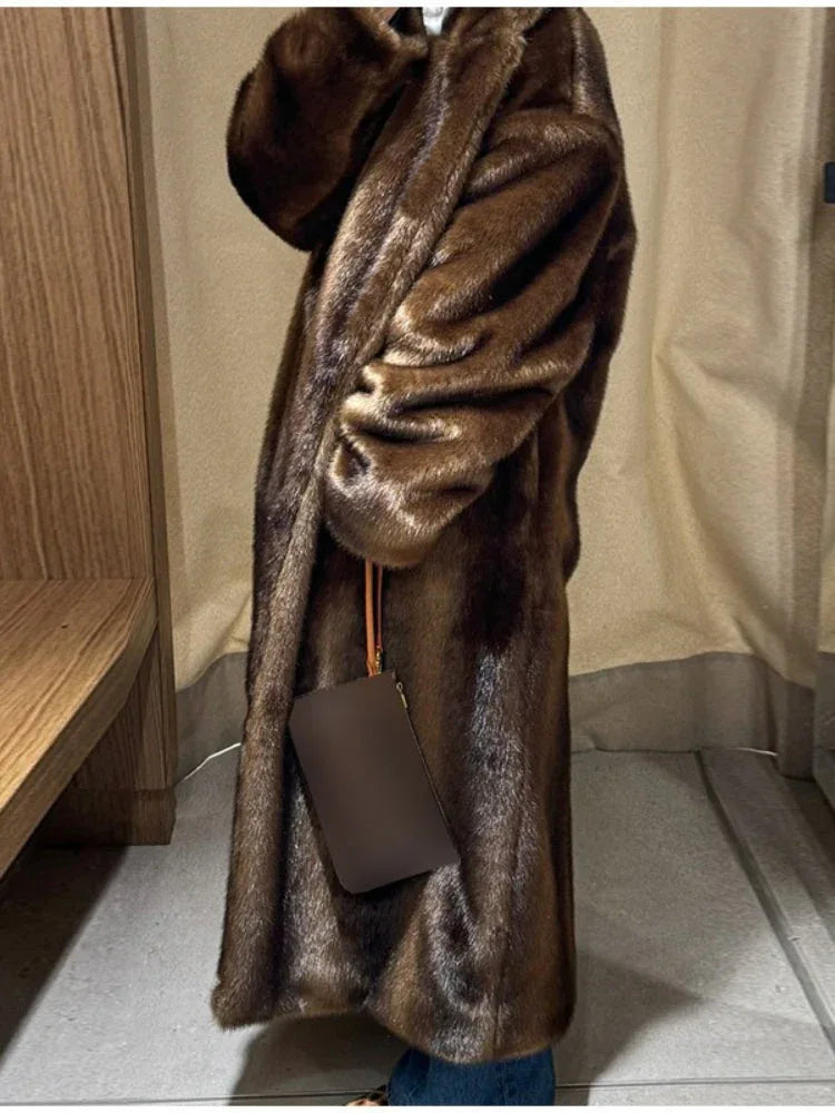 Side view of a woman wearing a long brown faux fur coat and blue jeans, holding a clutch.