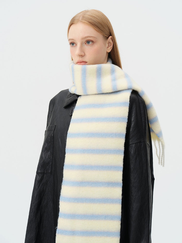 Close-up of a woman wearing a cream and light blue striped scarf with fringed ends.