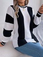 Woman sitting on a couch wearing a black and white striped knit sweater and blue jeans.