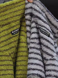 Close-up view of two pet sweaters, one lime green and one grey, with striped texture and brand tags